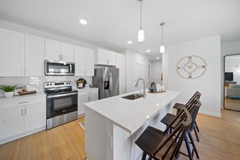 A modern kitchen with a white island and stainless steel appliances.